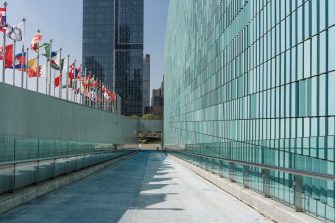 Modern glass curtain wall buildings with international flags lining a pedestrian corridor