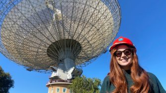 Master of Systems Engineering graduate Tori Tasker in front of a large radio telescope