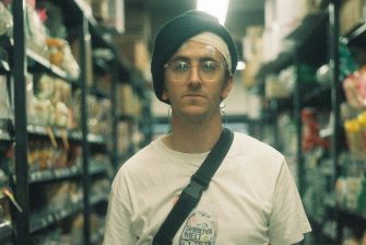 Young man standing between some packed shelves in a supermarket