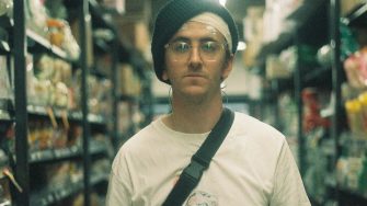 Young man standing between some packed shelves in a supermarket