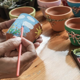 Person painting a garden pot
