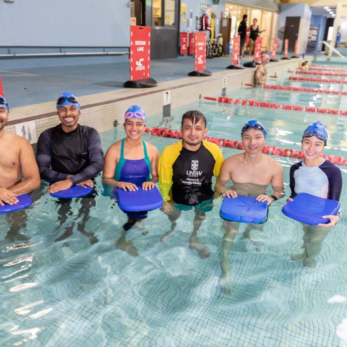 A group of students posing for a photo inside the pool as part of the Learn to Swim Program 