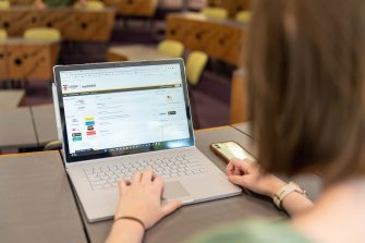 Student using a laptop at the top of a classroom