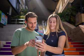 Two students looking at a phone with the Basser Steps in the background