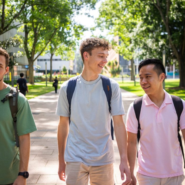 Three students chatting while walking on the Kensington Campus main walkway, University Mall