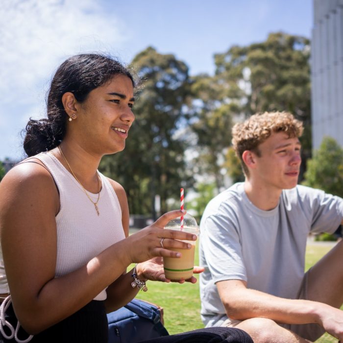 Students chatting and laughing on the grass at Alumni Park on the UNSW Kensington Campus