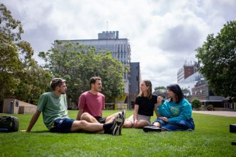 A group of students chatting while sitting on Globe Lawn on Kensington Campus