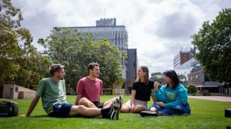 A group of students chatting while sitting on Globe Lawn on Kensington Campus