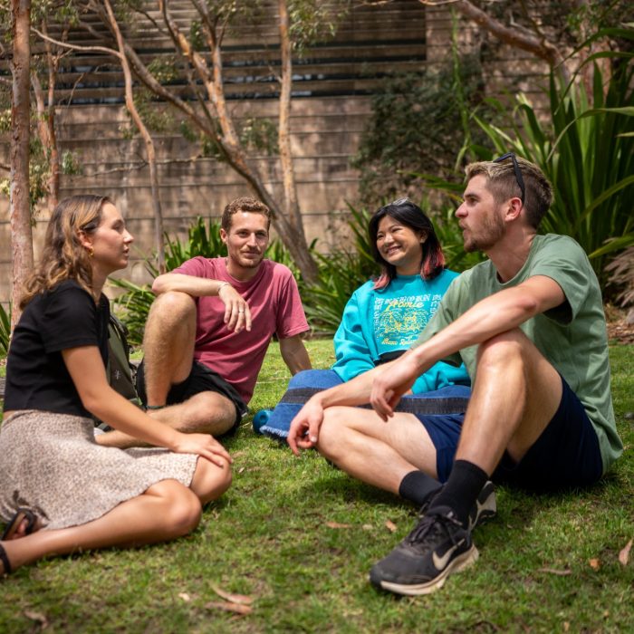 Four students chatting while sitting on Eleanora Kopalinsky Lawn on Kensington Campus