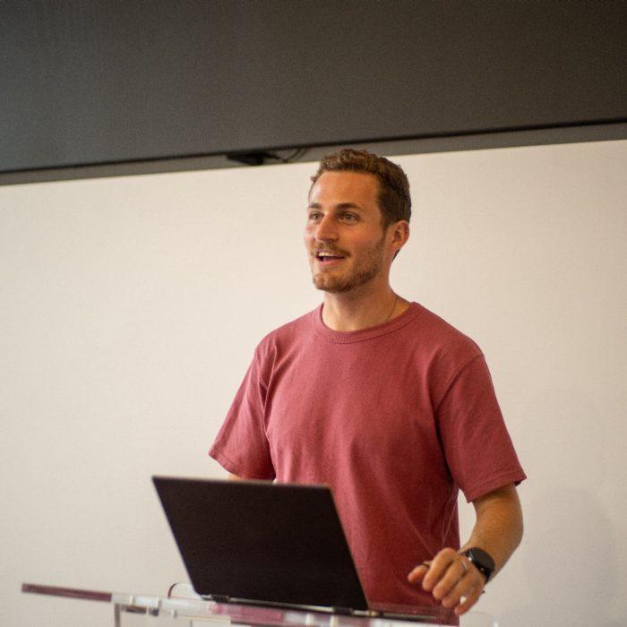 A student with a laptop giving a presentation at the top of a classroom