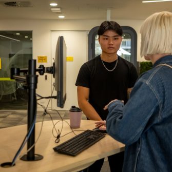 A student chatting to a staff member in the student hub on Paddington Campus