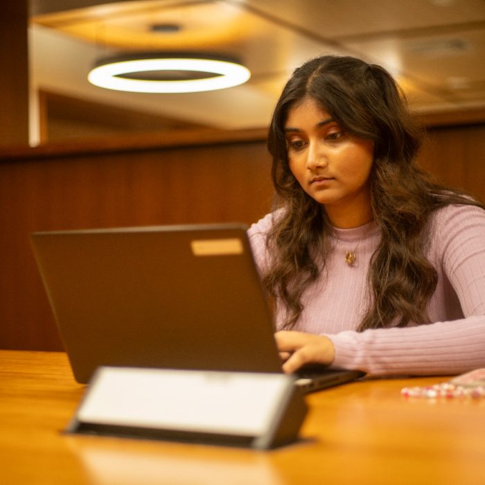 Students using their laptops at a shared desk in the library