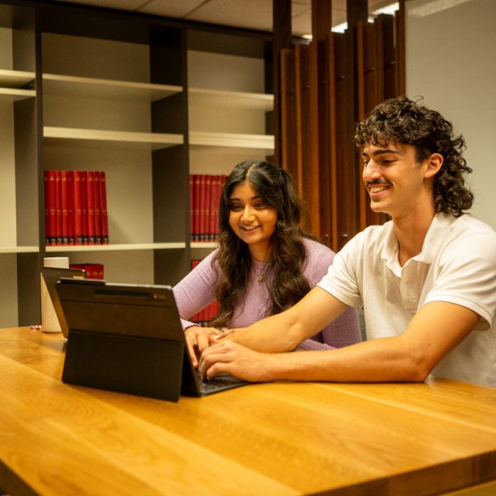 Students using their laptops at a shared desk in the library