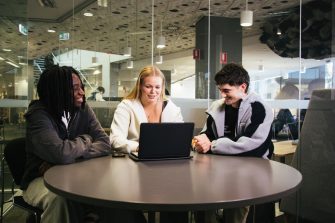 Students with a laptop sitting at a desk in the Law Library