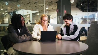 Students with a laptop sitting at a desk in the Law Library