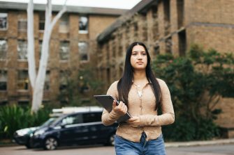 Student walking on campus with the Chancellery building in the background