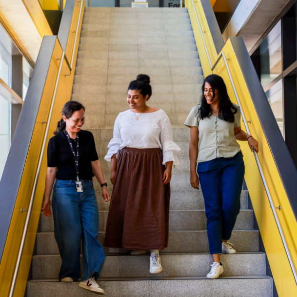 Three women walk down stairs smiling