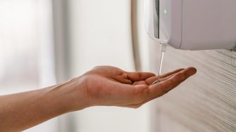 Woman hand using wash hand sanitizer gel dispenser automatic machine for prevent Coronavirus