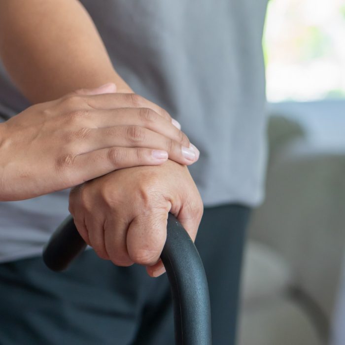 old senior woman with walking disability using cane as walking aid, with helping hand of care giver or nurse