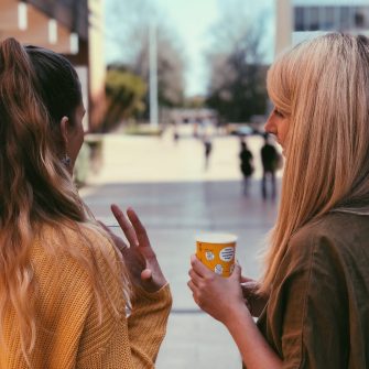 Two students photographed from behind engaged in discussion on campus