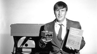 Associate Professor Jean Rueger holding a book and electronic device