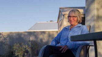 Nannette Helder sits outside in a chair on a patio