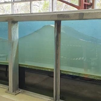The Water Research Laboratory’s 0.9 m wave flume measures approximately 36 m in length, 0.9 m in width, and 1.6 m in depth. The flume walls are primarily constructed of brick, with a large glass panelled section where models are constructed, allowing visual observations to be made throughout testing. The permanent floor of the flume is constructed of concrete, although site specific two-dimensional bathymetric profiles can be reproduced in the flume using an adjustable elevated timber floor system.