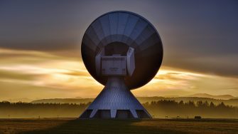A satelite dish backlit in the sunrise