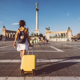 Young woman with suitcase just arriving in Budapest and walking through Heroâ  s square