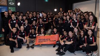 The entire Redback racing team posing for a photo with their racing xar