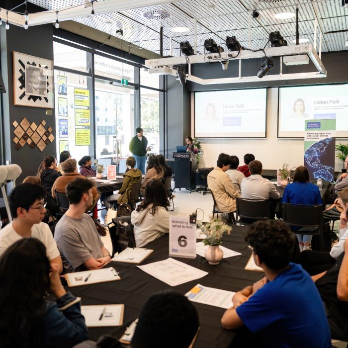 Participants seated at round tables facing a presentation at the UNSW–UTS TDS Student Forum.