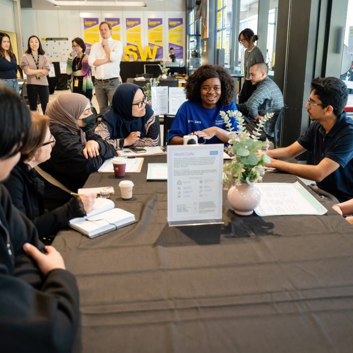 Participants smiling and exchanging ideas around a table at the UNSW–UTS TDS Student Forum.