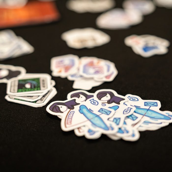 Close-up of colourful technology-themed stickers spread across a black table at the UNSW–UTS TDS Student Forum.