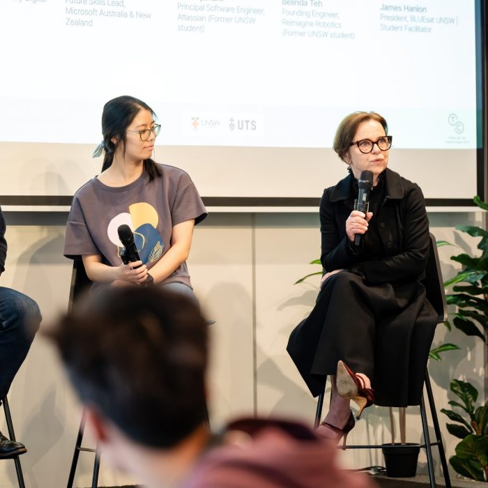 Three panellists seated on stools in front of a presentation screen at the UNSW–UTS TDS Student Forum.