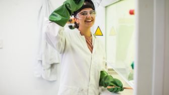 Student in workshop wearing personal protective equipment including gloves, coat, goggles and mask