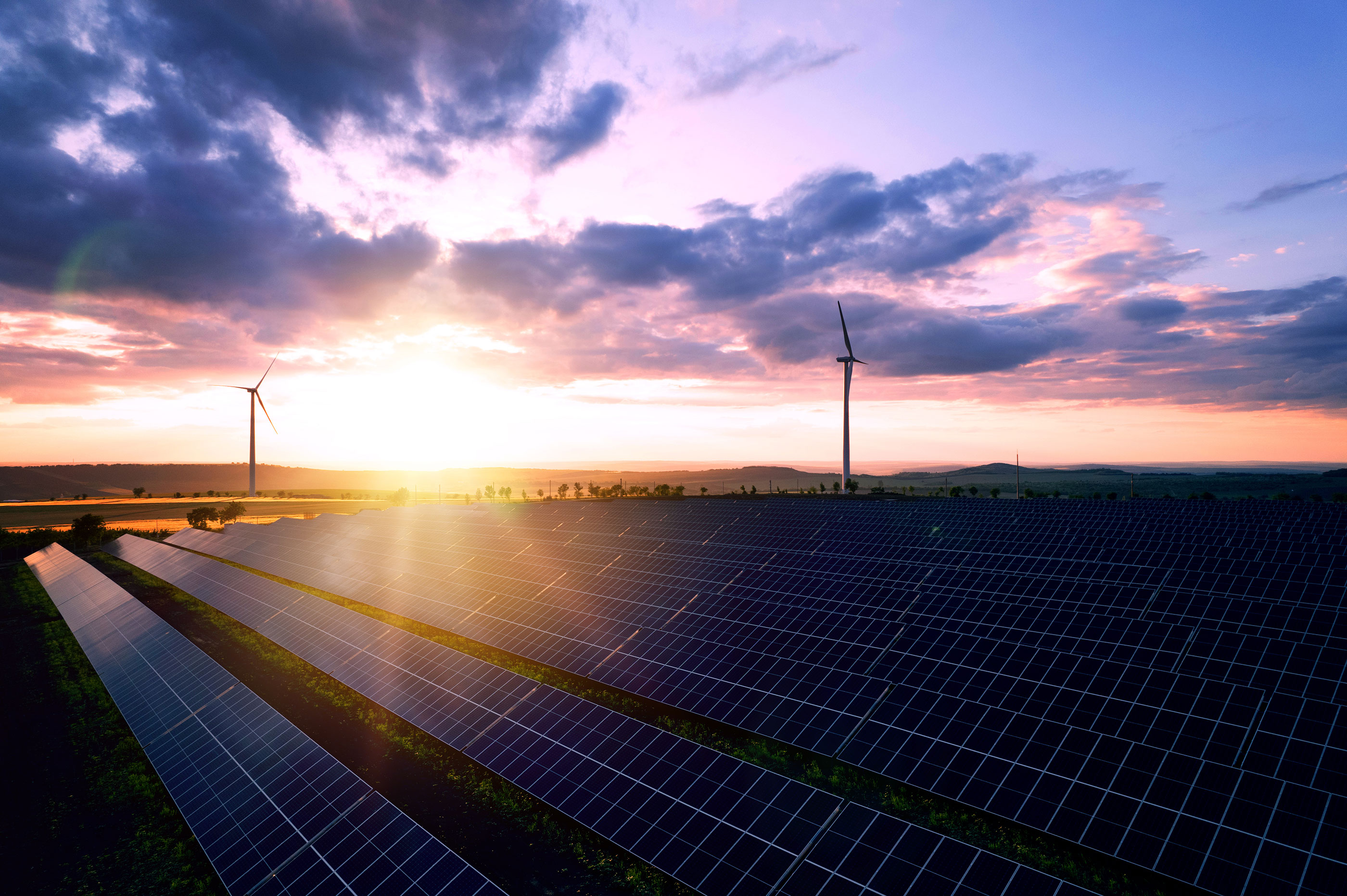 Solar panels park and wind turbines at sunset