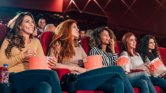 Stock image of girls eating popcorn at the movies