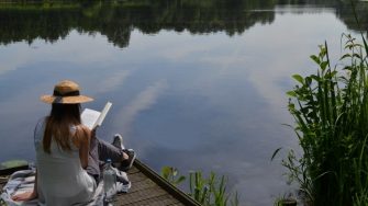 female reading by a lake