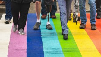 People walking across a rainbow crossing