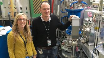 Scientists standing next to nuclear energy research equipment