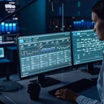 Female Software Engineer Working in a Modern Monitoring Office with Live Analysis Feed with Charts on a Big Digital Screen. Monitoring Room Big Data Scientists and Managers Sit in Front of Computers.
