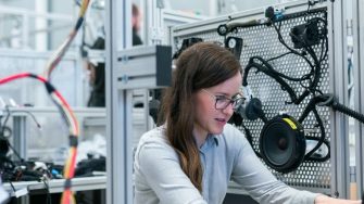 female engineer smiling in lab looking at laptop