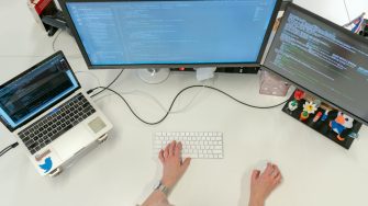 Woman coding on a computer with multiple screens