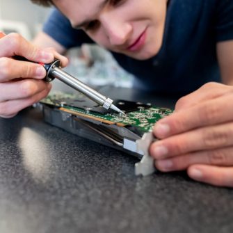 Close-up on an engineering student working on a robot and welding circuits