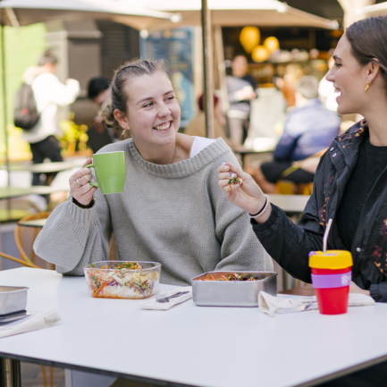Friends enjoying food and drinks with reusable cups and containers at a UNSW campus cafe.