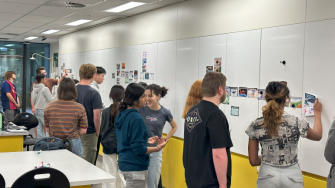 A group of people participating in a Climate Fresk workshop, placing cards on a large whiteboard wall.