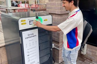 Student dropping a bottle into a white smart bin
