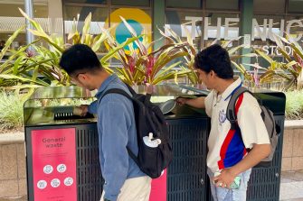Students dropping waste into red general waste bins