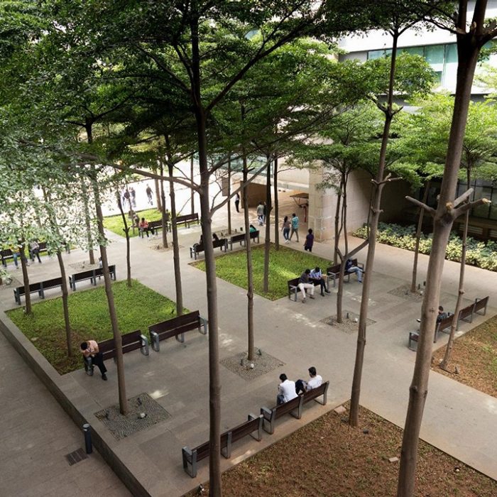 Arial view of a courtyard in Manyata Business Park with tall trees, outdoor seating and green spaces.