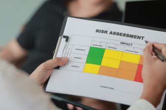 Professional analysing risk assessment matrix on clipboard